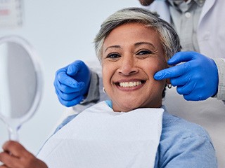 Woman smiling while holding small mirror