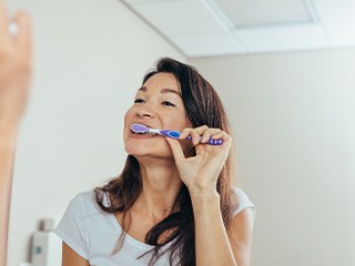 Woman brushing her teeth in bathroom