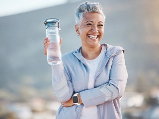 Woman smiling with water bottle on hike outside