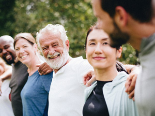 Line of adults outside with arms linked smiling at each other