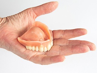 Hand holding full dentures in McComb, OH	