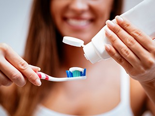 young woman putting toothpaste on toothbrush