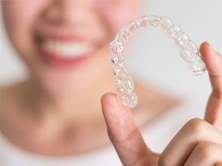 A woman holding an Invisalign aligner