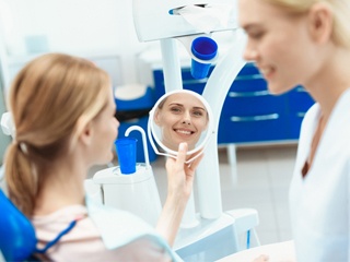 A woman looking at her smile in the mirror at her dentist office