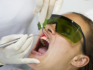 Dentist treating gum disease with laser dentistry.