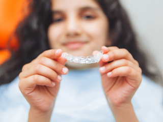 Teen girl holding clear aligner
