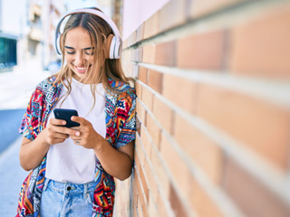 Teen girl smiling while looking at phone outside
