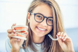 person holding Invisalign and braces