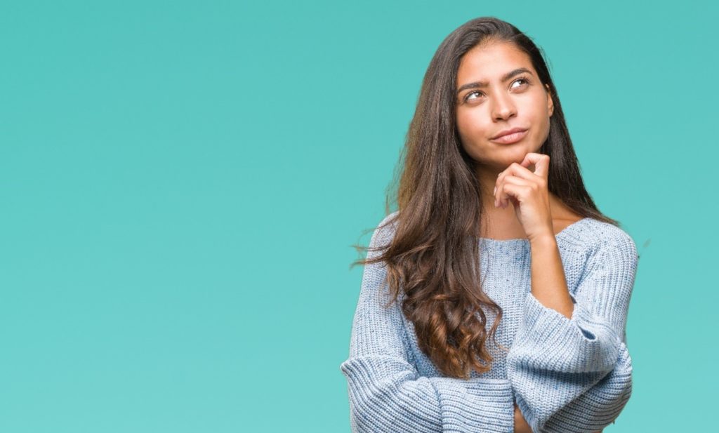 Woman in blue sweater wondering about Invisalign after braces