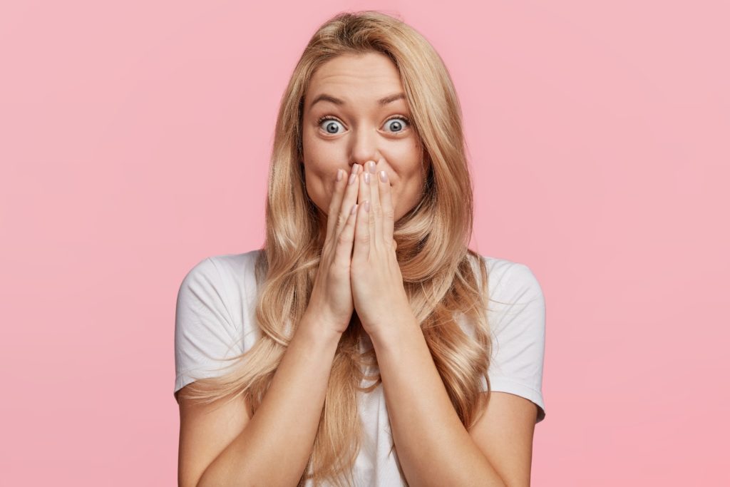 Closeup of excited woman covering her mouth