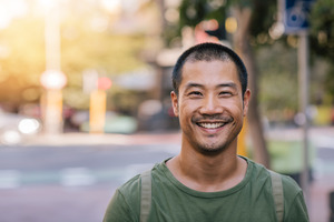 Man in green shirt smiling and walking down the street