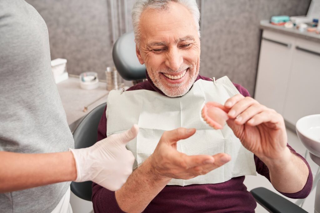Patient smiling while holding model of denture