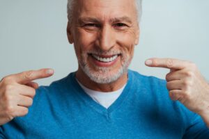 Man smiling and pointing to his dentures